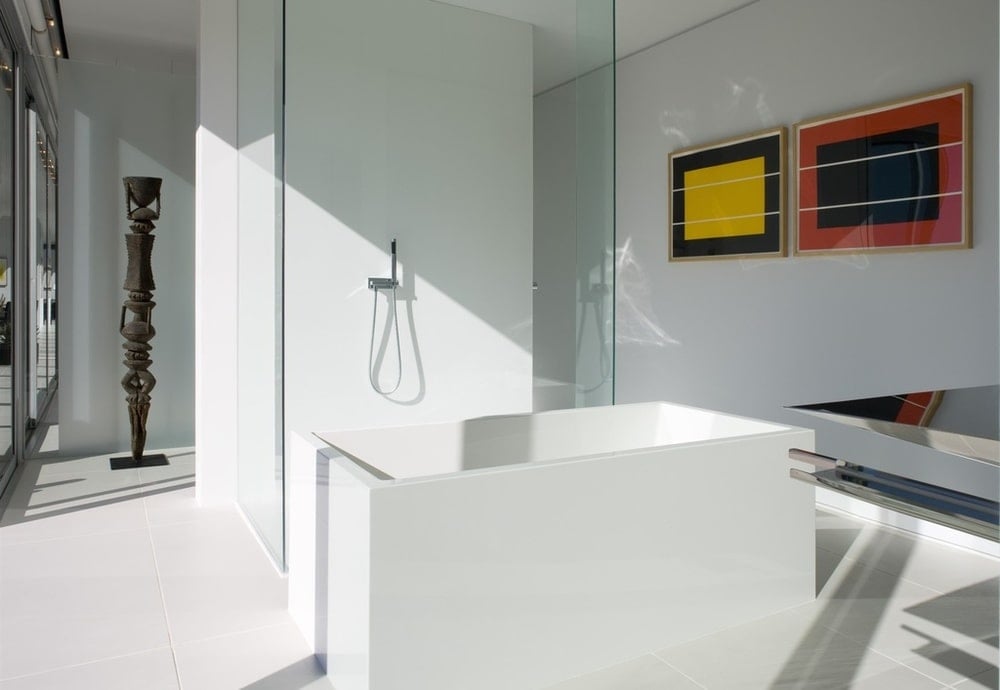 This is the bathroom with a modern white bathtub next to the glass wall of the shower area. Image courtesy of Toptenrealestatedeals.com.