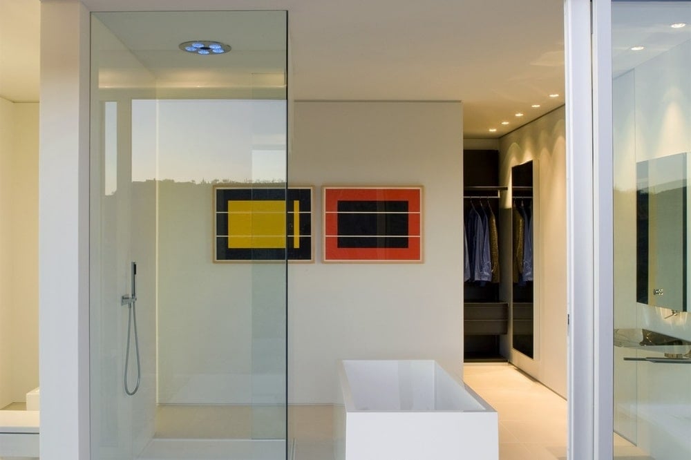 This other look at the bathroom shows the glass wall and the colorful wall-mounted artworks that bring a dash of color to the bright bathroom. Image courtesy of Toptenrealestatedeals.com.