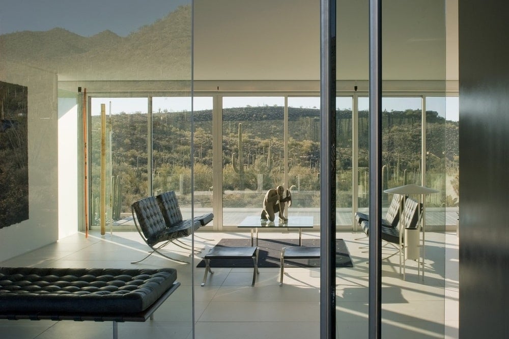 This is a look at the living room area from the vantage of the glass door. You can see here the black leather cushions of the chairs and benches that stands out against the brightness of the floors and walls. Image courtesy of Toptenrealestatedeals.com.