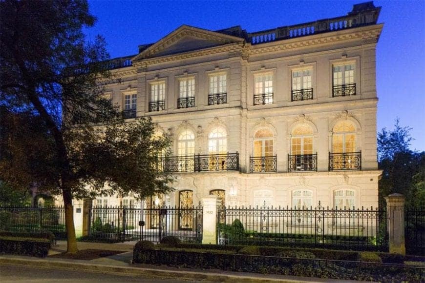 This is a front look at the mansion with three levels, multiple windows and wrought-iron fencing, all complemented by the lighting.