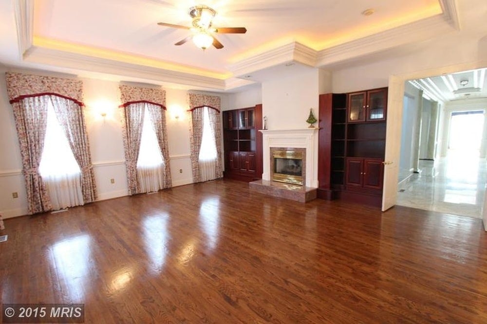This family room has a wide hardwood flooring that matches well with the built-in wooden cabinets and shelves flanking the fireplace. Image courtesy of Toptenrealestatedeals.com.