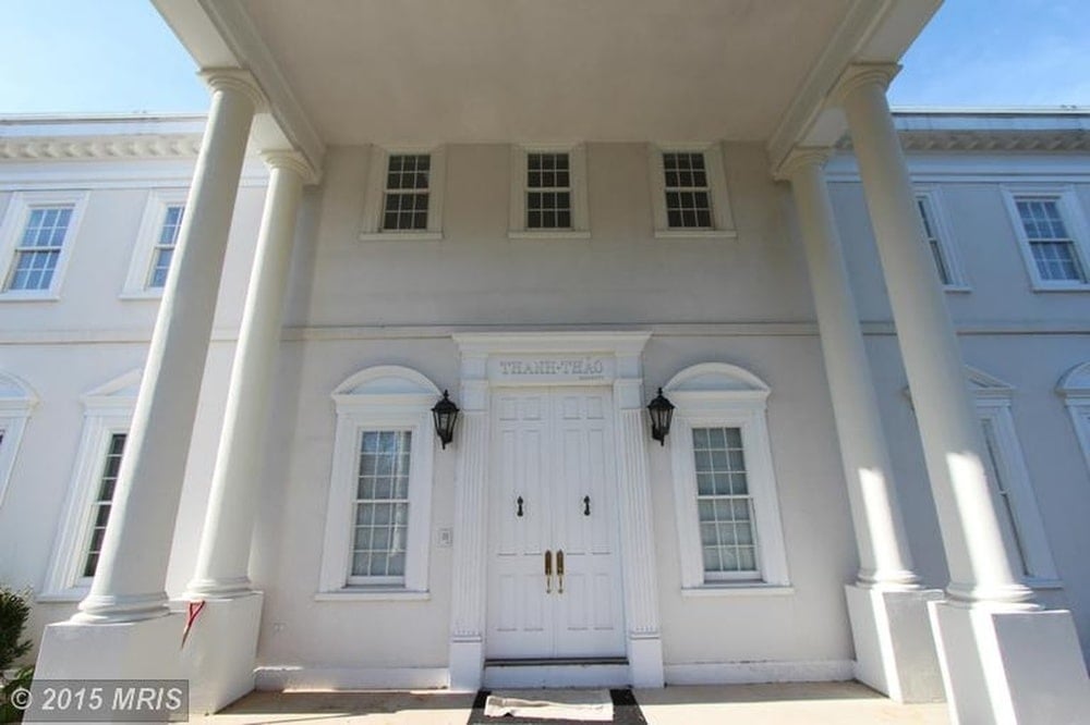 This is a closer look at the main entrance of the house with a white main door flanked by windows and wall sconces. Image courtesy of Toptenrealestatedeals.com.