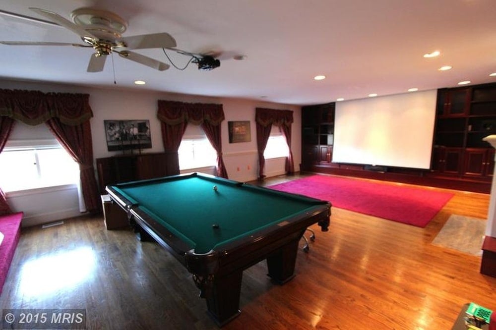 This is a look at the game room of the house fitted with a large pool table that matches the hardwood flooring. Image courtesy of Toptenrealestatedeals.com.