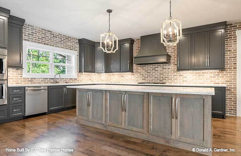 A pair of candle pendant lights hanging above the wooden center island illuminate the kitchen.