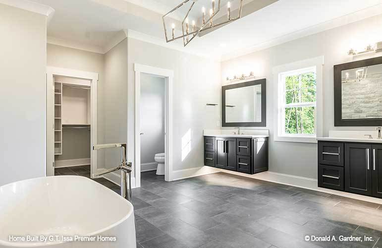 The primary bathroom is equipped with two sink vanities, a toilet room, and a freestanding tub paired with a chrome faucet.