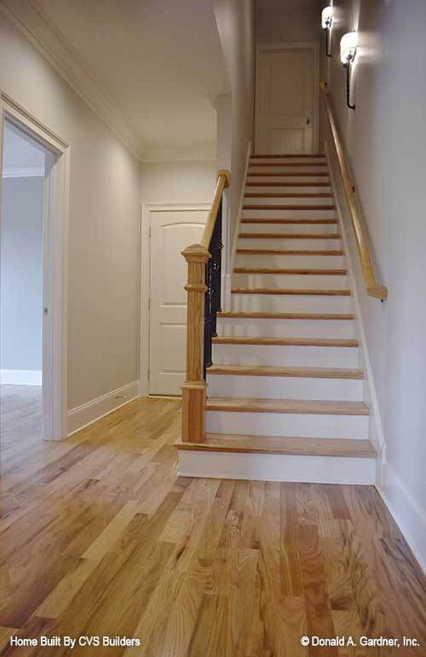 A traditional staircase with white risers and wooden treads matching with the light hardwood flooring.