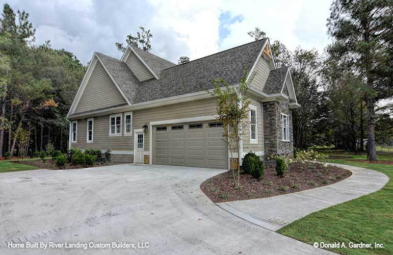 Side exterior view with an oversized garage complemented with a concrete driveway and manicured shrubs.