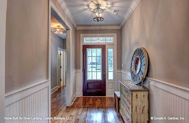 Foyer with a wooden entry door, semi-flush light, and a rustic console table topped with a round clock.