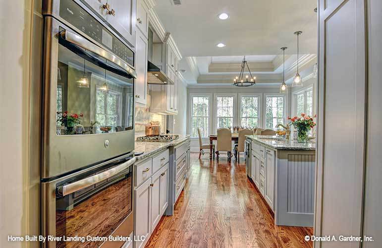 Galley kitchen overlooking the dining area that's crowned with a step ceiling.