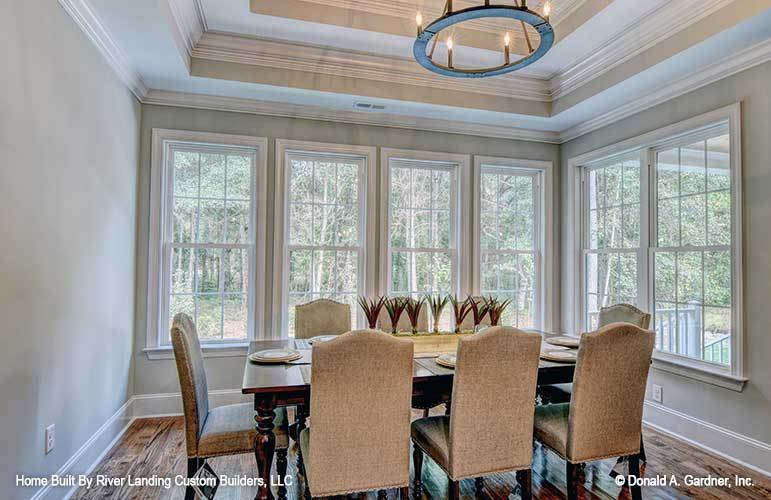 The dining area offers beige upholstered chairs, dark wood dining table, round chandelier, and plenty of white-framed windows.