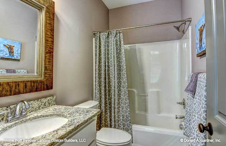 The other bathroom is equipped with a sink vanity, a toilet, and a tub and shower combo enclosed in a patterned curtain.