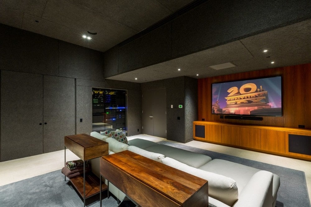The home theater room has a large wall-mounted screen at the far wall across from the large comfortable couch that stands out against the dark gray walls and ceiling. Image courtesy of Toptenrealestatedeals.com.