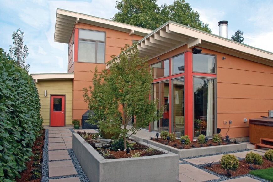 Side exterior view with a concrete planter and a vibrant red door leading to the double garage.