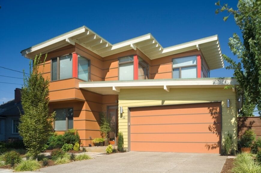 Home facade with warm horizontal siding, corner glass windows, and flat roofs.