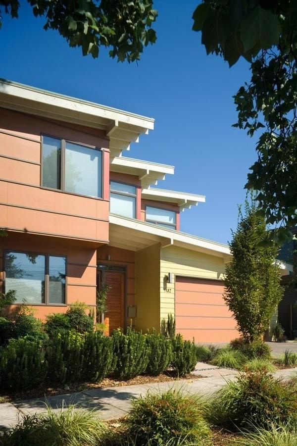 A closer view of the home entry showcasing a wooden front door complemented with lush green plants.