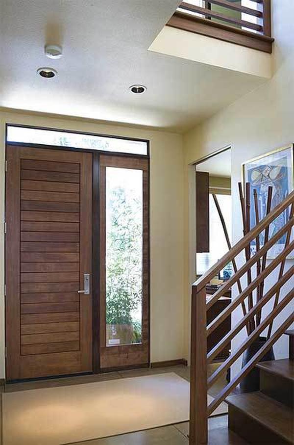 Foyer with a wooden front door, brown rug, and a framed artwork adorning the beige wall.
