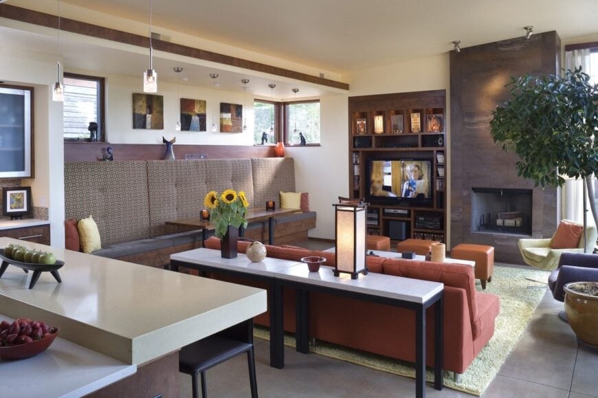 A dining area lies next to the living room while the kitchen is situated at the back of the terracotta sofa.