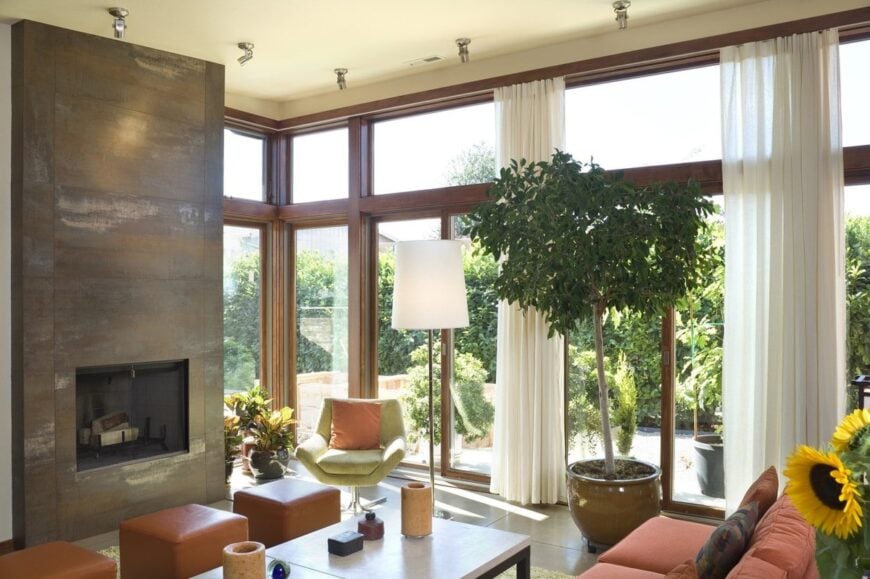The living room offers comfy fabric and leather seats, a stone fireplace, and full-height glazing that brings an abundance of natural light in.