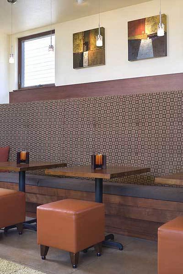 The dining area offers small wooden tables paired with a leather ottoman and a built-in cushioned bench.