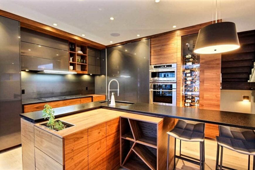 The kitchen is equipped with slate cabinets, an L-shaped island, and a glass-enclosed wine rack fitted on the wooden cabinet.