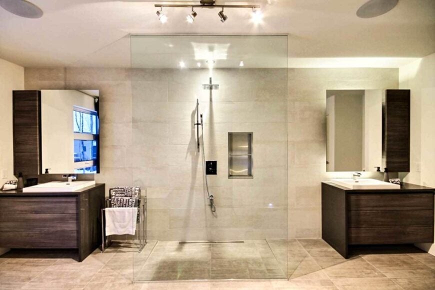Primary bathroom with a walk-in shower nestled in between the wooden vanities.