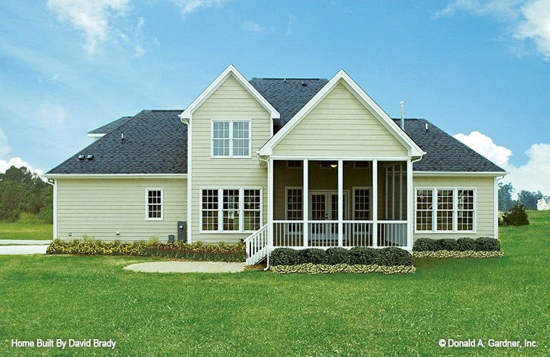 Rear exterior view showing the screened porch graced with manicured shrubs.