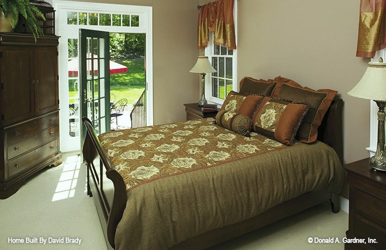 Primary bedroom with dark wood furnishings, beige carpet flooring, and private access to the patio.