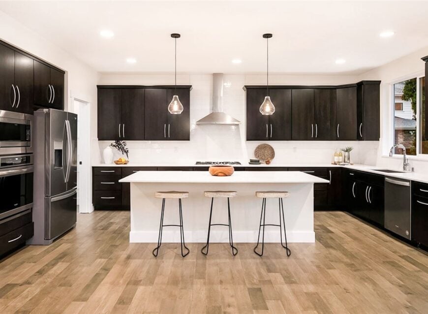 The kitchen is equipped with dark wood cabinetry, stainless steel appliances, quartz countertop, and a white breakfast island.