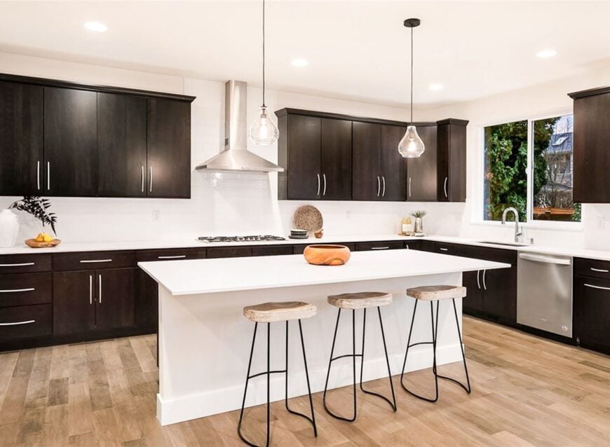 A pair of glass pendants along with wooden bar stools complement the center island.