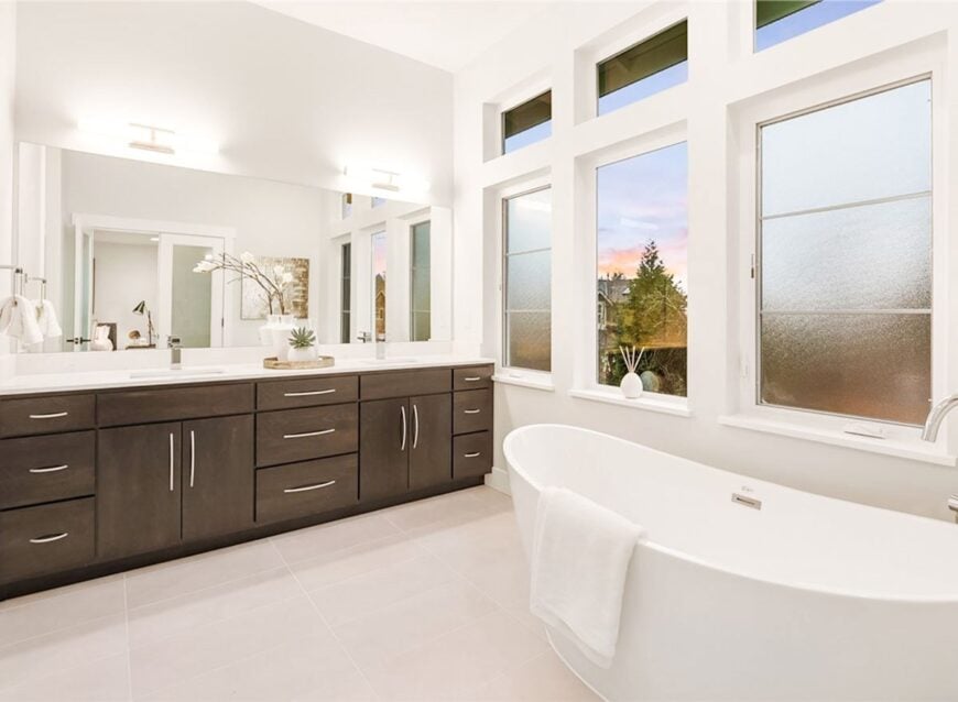 The primary bath has a freestanding tub and a dual sink vanity paired with a rectangular frameless mirror.