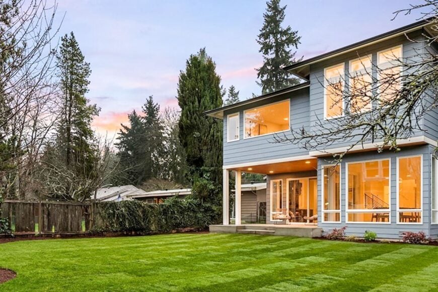 The angled view shows the towering trees and wooden fence covered in creeping plants.