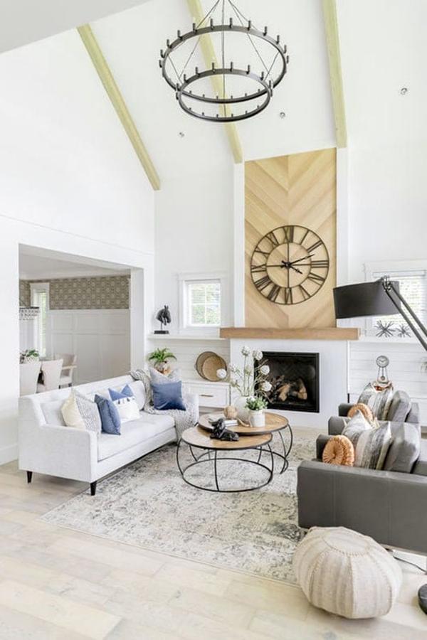 Living room with gray seats, modular coffee table, modern fireplace, and a two-tier chandelier hanging from the cathedral ceiling with exposed beams.