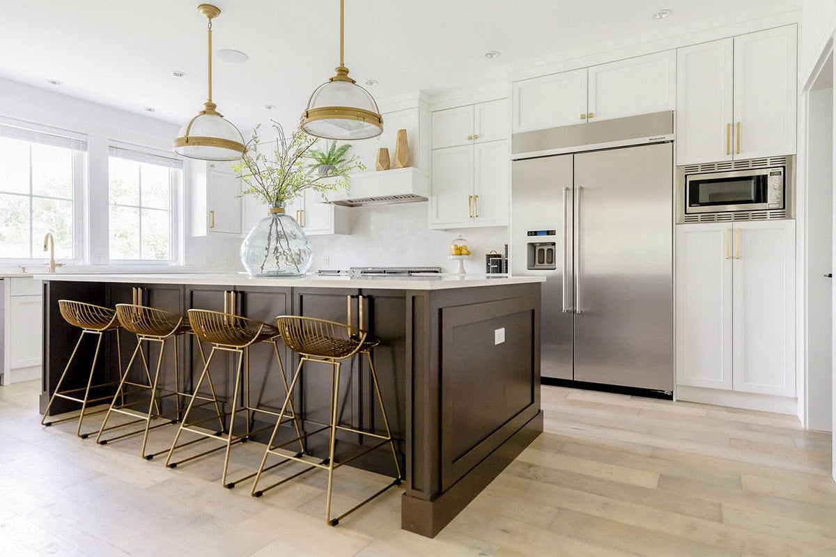 Kitchen with top of the line appliances, wooden island, and white cabinetry accented with brass hardware.