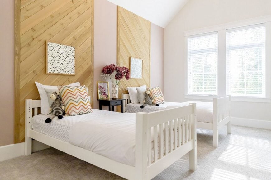 This bedroom offers two beds and a dark wood center nightstand topped with a frame and vase.