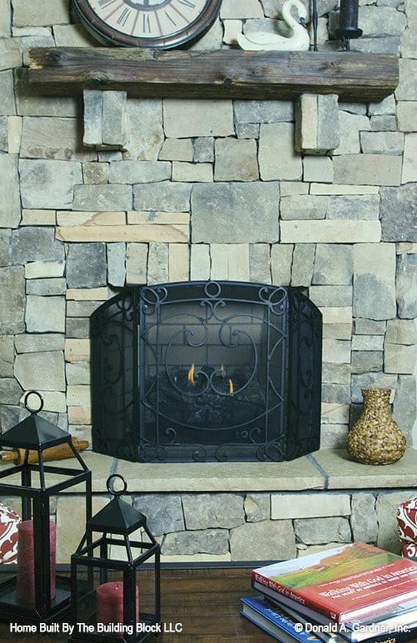 A closer look at the stone fireplace showing its rustic mantel and ornate wrought iron panel.