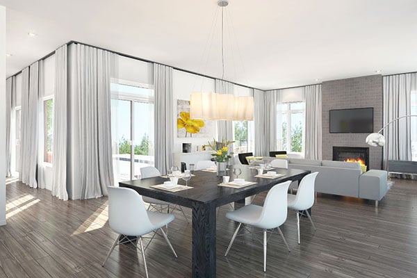 Shared living and dining room with a fireplace, gray sofa, white modern chairs, and a dark wood table well-lit by a glass chandelier.