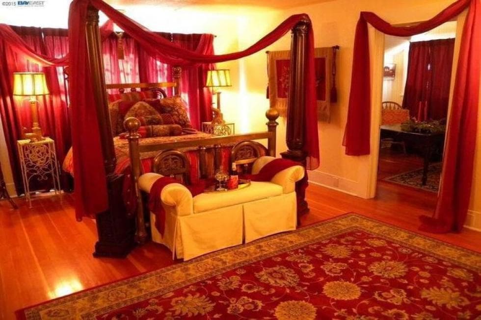 This other bedroom has a red theme to its area rug, bed and wall accents that go well with the beige walls. Image courtesy of Toptenrealestatedeals.com.