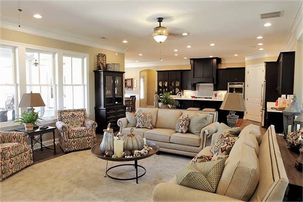 The living room has beige sectionals, patterned armchairs, and a round coffee table sitting on a velvet area rug.