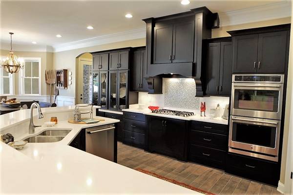 Kitchen equipped with stainless steel appliances, black cabinets, marble countertops, and a double bowl sink fitted on the two-tier island.