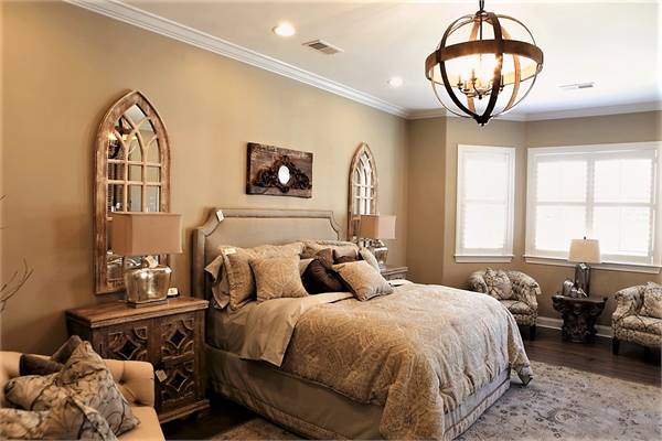 Primary bedroom with a bayed sitting area and a beige upholstered bed flanked by stylish nightstands and arched mirrors.