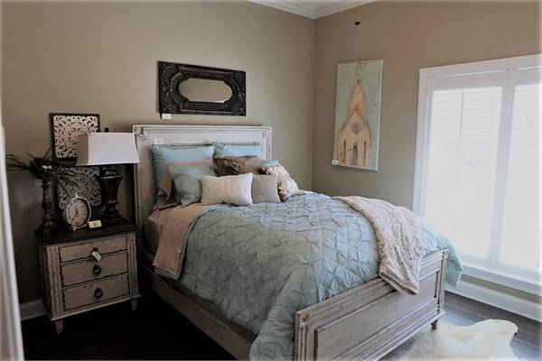 This bedroom has light wood furnishings, white-framed windows, and a white faux fur rug.