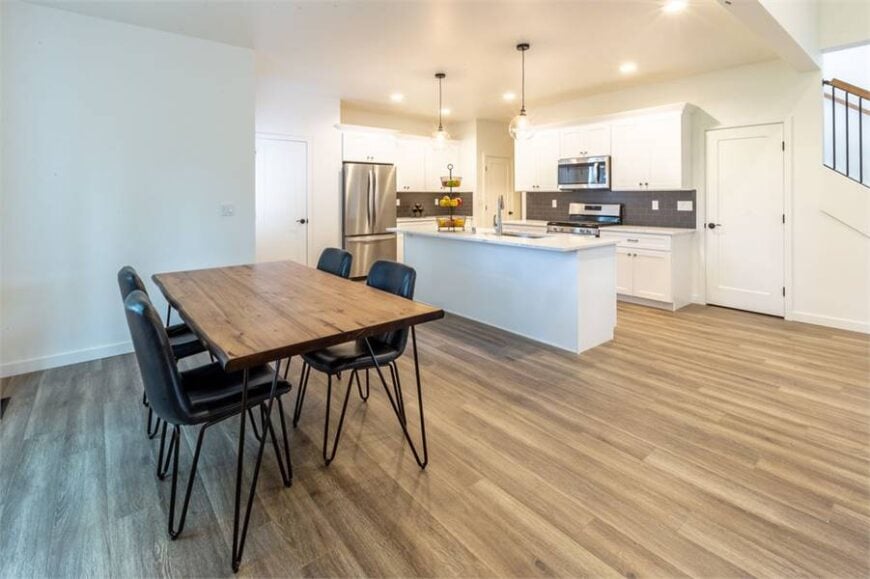 The dining area offers black leather chairs and a rectangular dining table that matches the hardwood flooring.