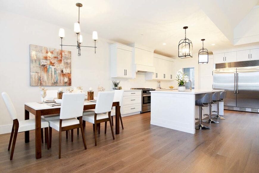 The eat-in kitchen offers a rectangular dining set, white cabinetry, stainless steel appliances, and a breakfast island.
