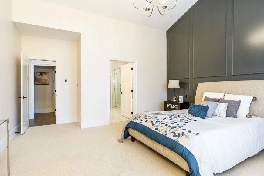 The primary bedroom has a full ensuite, dark wood nightstand, and a beige upholstered bed that blends in with the hardwood flooring.