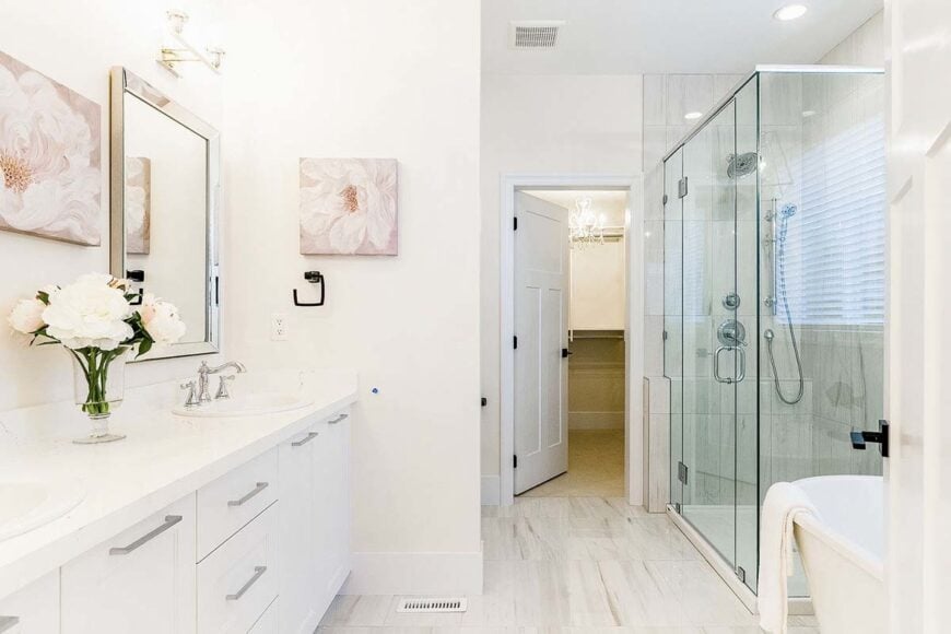 Primary bathroom with his and her sink vanity, freestanding tub, glass-enclosed shower, and a walk-in closet.