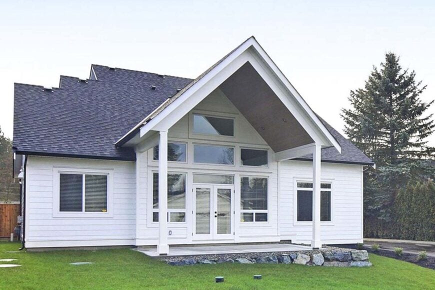 Rear exterior view showing the covered patio with slim columns, concrete floor, and a cathedral ceiling.