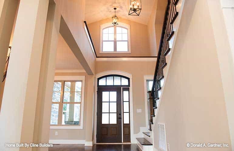 The foyer has a high vaulted ceiling, dark wood entry door, and lantern pendants.