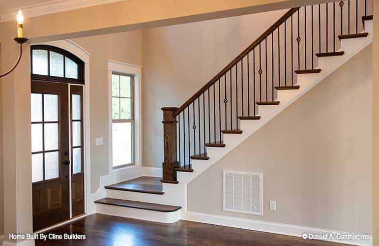 Staircase with wooden treads and handrails matching with the front door.