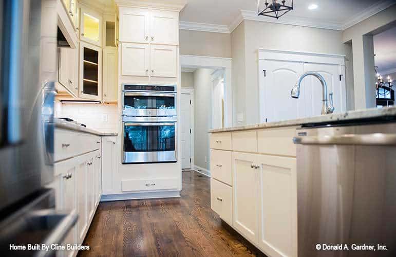 Double-wall oven and a walk-in pantry with a white double door complete the kitchen.