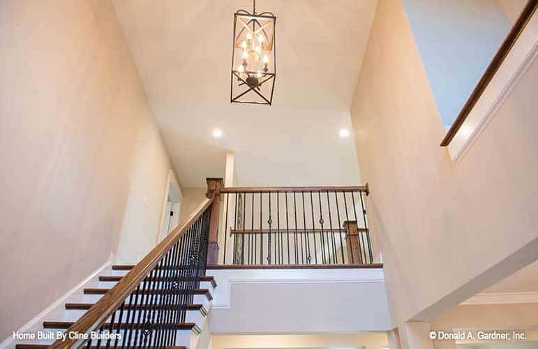 A large pendant light hanging from the high regular ceiling illuminates the staircase.